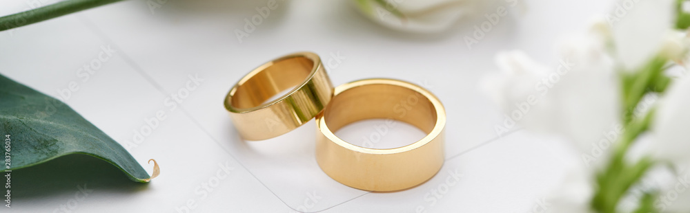 selective focus of golden wedding rings on white envelope, panoramic shot selective focus of golden wedding rings on white envelope, panoramic shot