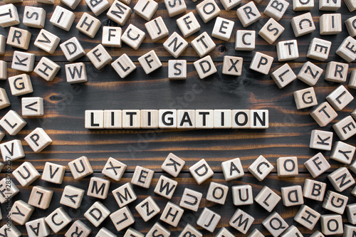 litigation - word from wooden blocks with letters, the process  determining issues a court Arbitration and Litigation concept, random letters around, top view on wooden background photo