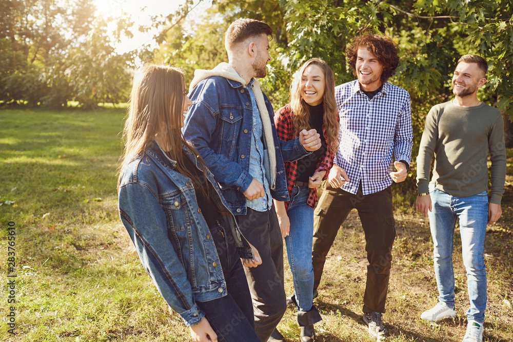Young people laugh while standing in a park in spring. Young people laugh while standing in a park in spring.