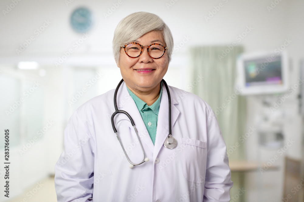 Senior Asian doctor woman with smiling face on the background of the modern hospital Senior Asian doctor woman with smiling face on the background of the modern hospital
