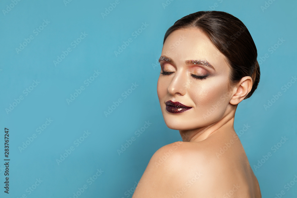 Beautiful young woman with glitter makeup on blue background, space for text Beautiful young woman with glitter makeup on blue background, space for text