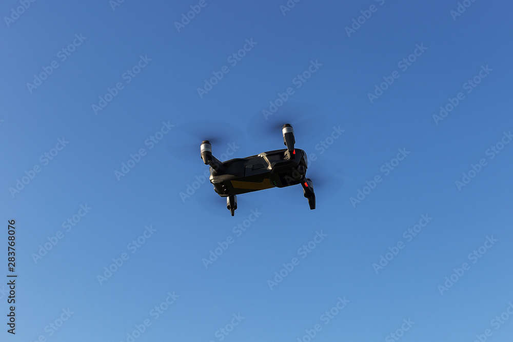 A drone, a quadrocopter with a camera for video shooting, flies against a blue sky. A drone, a quadrocopter with a camera for video shooting, flies against a blue sky.