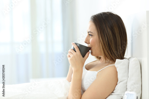 Profile of a woman drinking coffee on the bed