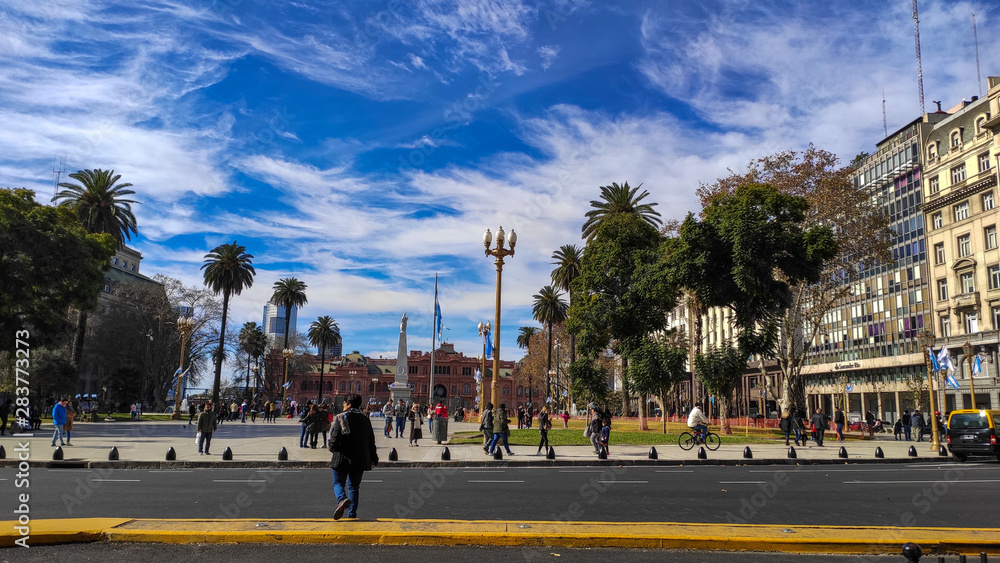 Casa Rosada in argentina in the middle of the afternoon with a large square in front, with a big blue sky behind 