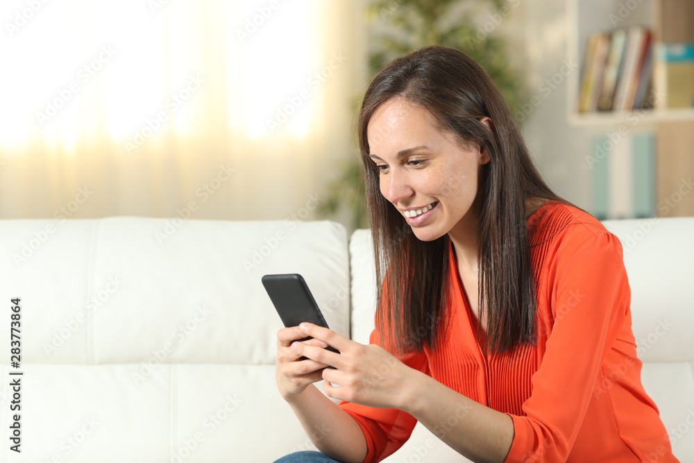 Woman in orange at home using a smart phone Woman in orange at home using a smart phone