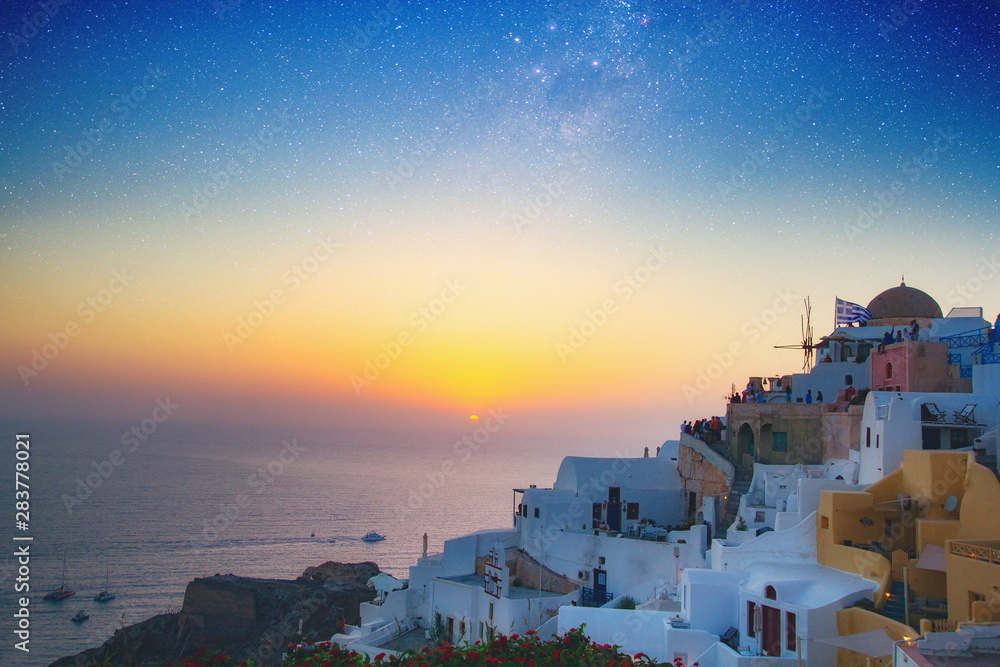 Fototapeta premium Magnificent view of the mills of the city of Oia on the island of Santorini Greece during a beautiful sunset in the Mediterranean. Love and travel background. Elements of this image furnished by NASA.