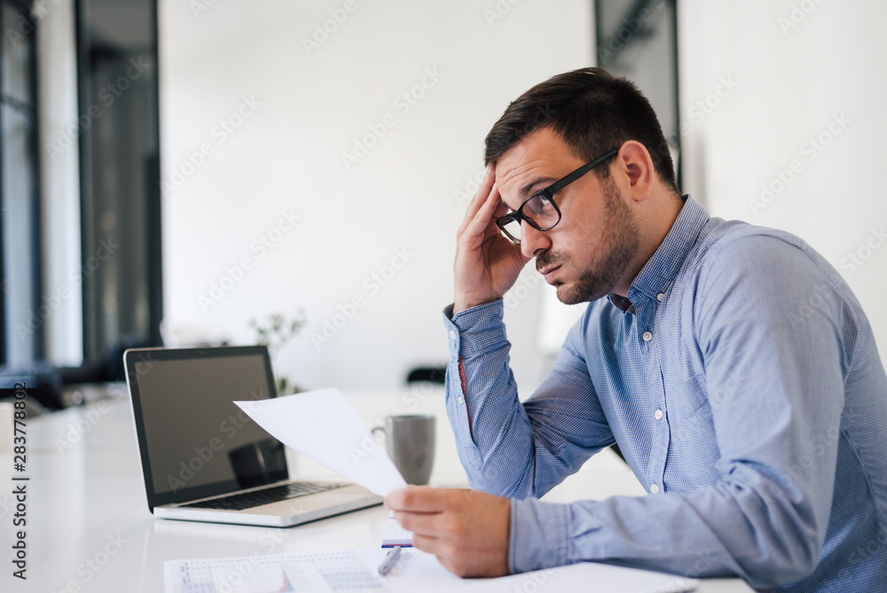 Stressed out and worried overworked businessman in office working under pressure and tight deadline Stressed out and worried overworked businessman in office working under pressure and tight deadline
