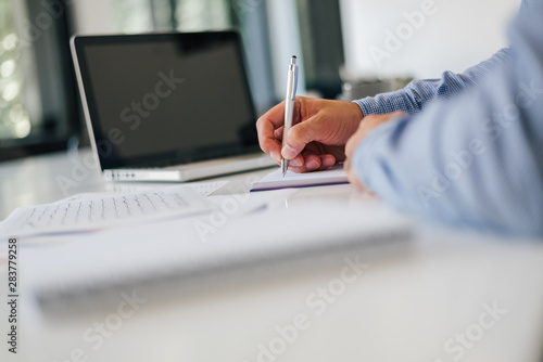 Close up of businessman hand taking notes in modern office and planing work or workflow