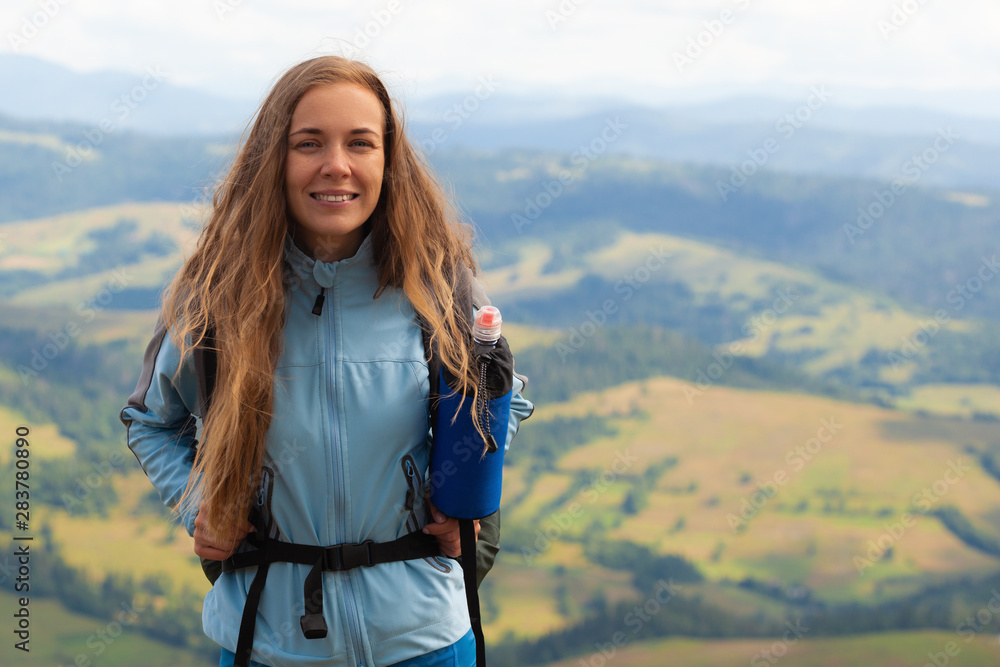 Hiking. Woman hiker smiling standing outside at the top of a hill with backpack. Outdoor portrait of happy beautiful young woman. Hiking. Woman hiker smiling standing outside at the top of a hill with backpack. Outdoor portrait of happy beautiful young woman.