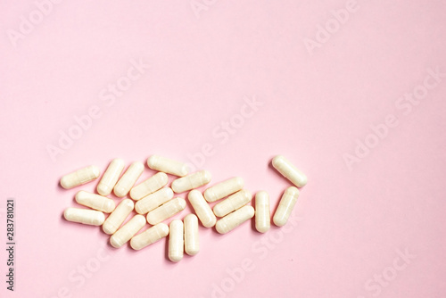 White capsule sour milk bacteria. Biological supplement for the stomach on a pink background.