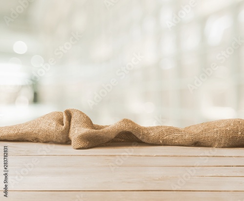 Canvas Print Burlap texture on wooden table on blurred background