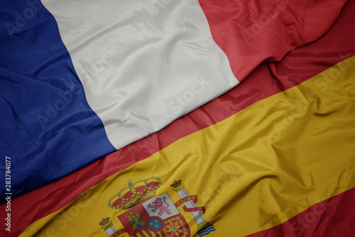 waving colorful flag of spain and national flag of france. photo