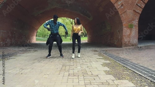 Cool latino girl calling a black man and after they dancing together outside in the park 