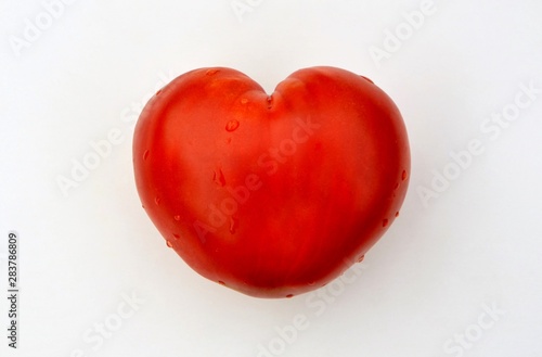Bright red heart shaped tomato on white background close up © Irina