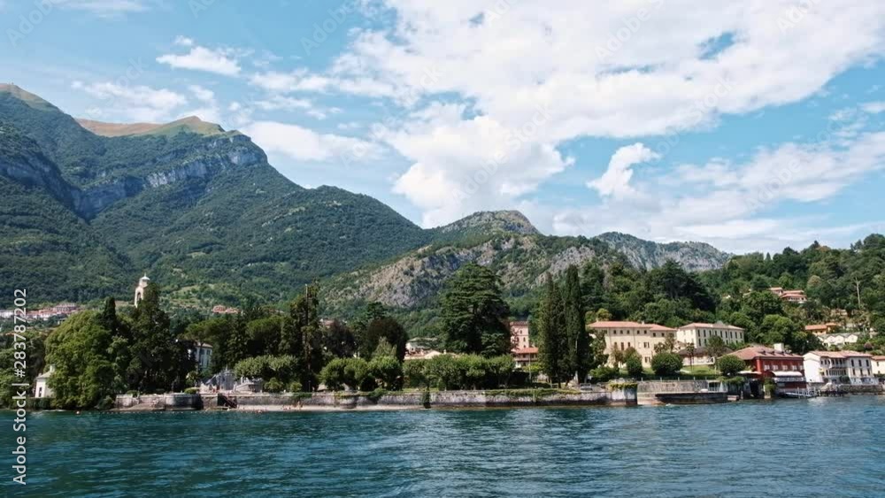 Cinematic shot of Bellagio town, Como lake and mountains from a boat in Lombardy, Italy Cinematic shot of Bellagio town, Como lake and mountains from a boat in Lombardy, Italy