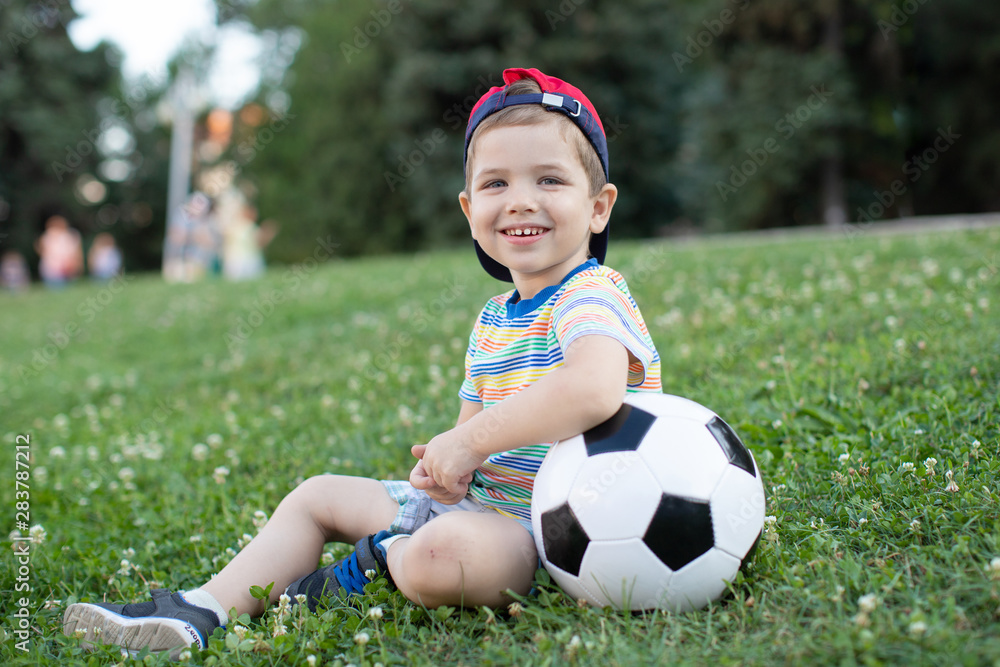 Happy blond little boy of 4 playing soccer with football on football field, outdoors. Happy blond little boy of 4 playing soccer with football on football field, outdoors.