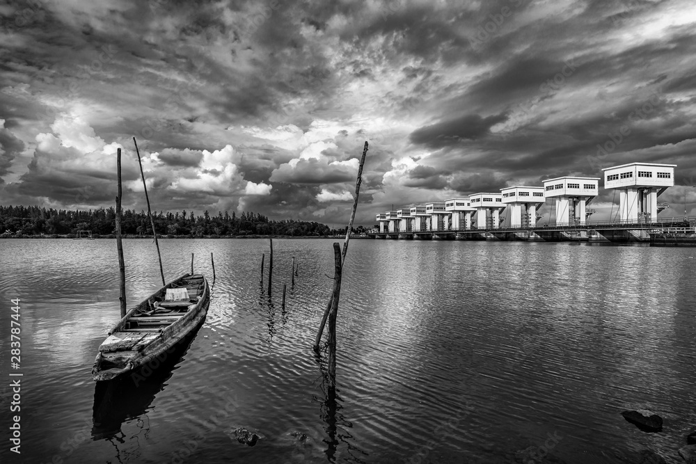 Fishing boat and water barrier and river with cloud sky storm, Black and white and monochrome style