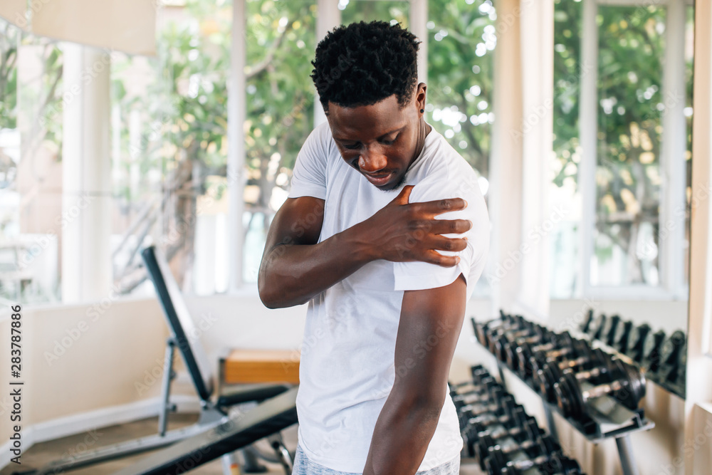 Ταπετσαρία Side view of muscular African American man standing and suffering from shoulder pain during workout with dumbbells