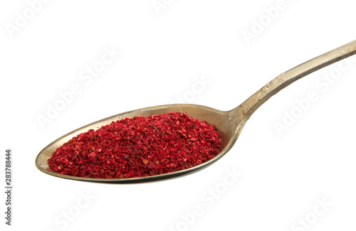 Chopped red pepper in a spoon isolated on a white background. View from above. Spices on isolate. photo