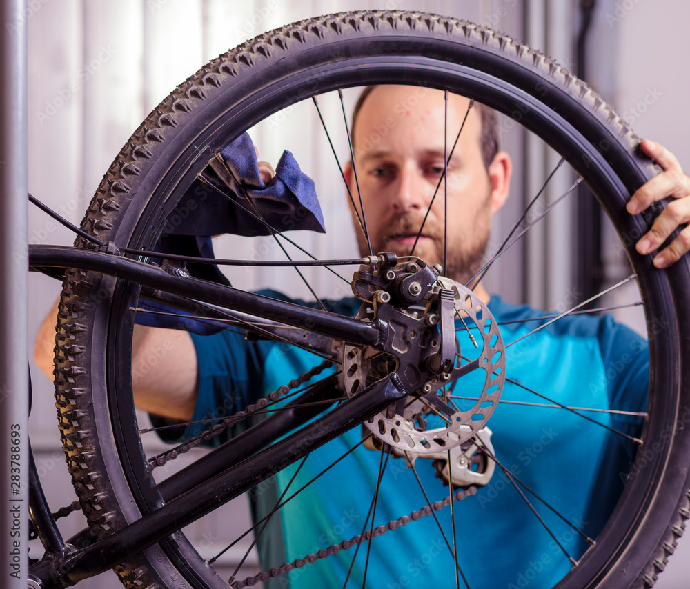 Mechanic in a bicycle repair shop oiling the chain of a bike. Man