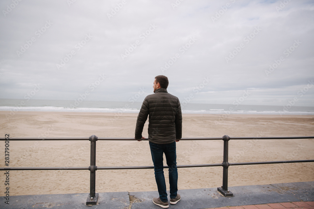 Back view of man in khaki jacket looking on the North Sea