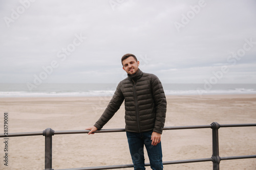 Handsome man standing in front of North Sea. Stylish man in khaki jacket © Aleksandr