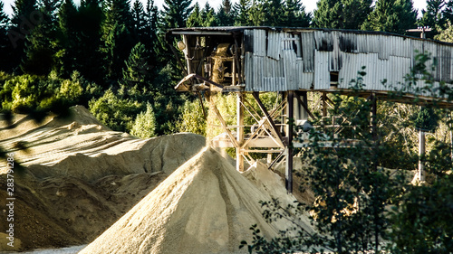 a mountain of sand lies in the concrete factory where and a conveyor belt for transporting the sand photo