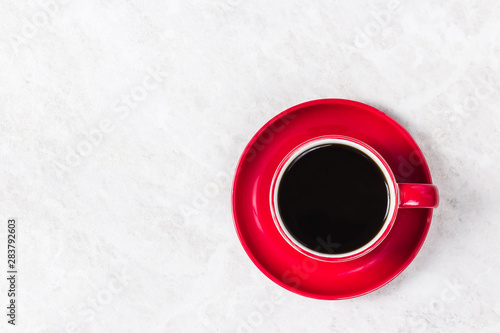 Black coffee in red cup on white marble background. Top view, space for text.