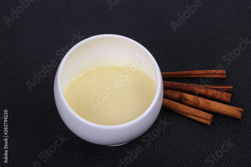 Condenced milk in the bowl with sinnamon and pastry photo