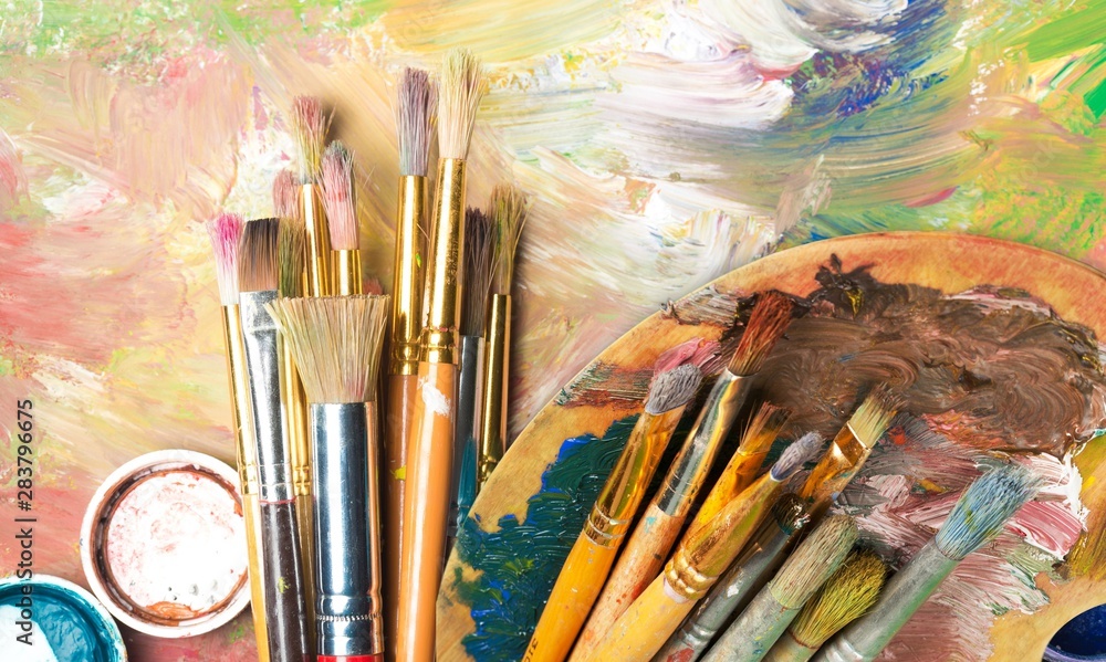 Fototapeta premium Artist paint brushes and paint cans of paint over bright watercolor background