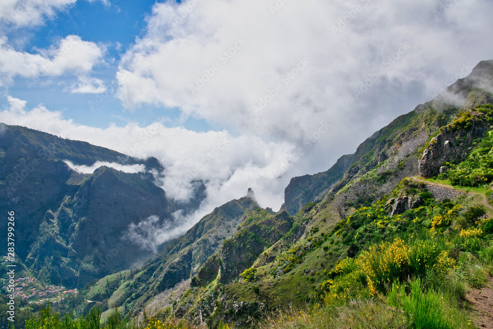 View from the hiking trail at the Boca da Corrida belvedere on the Encumeada pass on Madeira Island, Portugal in summer, View to the village of Curral das Freiras View from the hiking trail at the Boca da Corrida belvedere on the Encumeada pass on Madeira Island, Portugal in summer, View to the village of Curral das Freiras