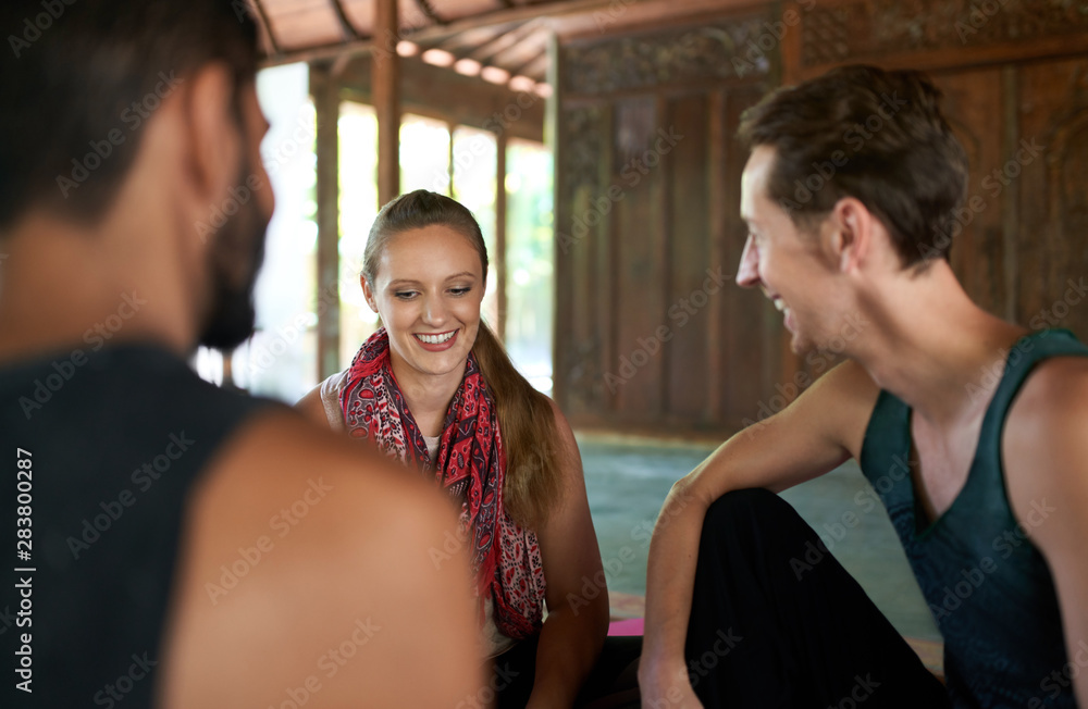 Candid shot of three diverse friends discussing together after yoga class in traditional temple in Bali, Indonesia Candid shot of three diverse friends discussing together after yoga class in traditional temple in Bali, Indonesia