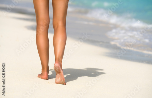 Close-up of female legs in the blue water on the tropical beach. Vacation holidays.