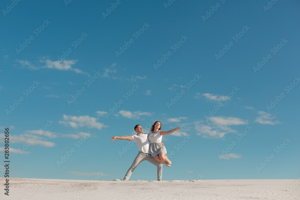 Romantic couple dancing in sand desert at blue sky background