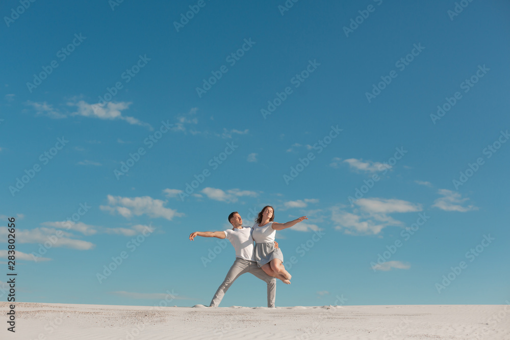Romantic couple dancing in sand desert at blue sky background Romantic couple dancing in sand desert at blue sky background