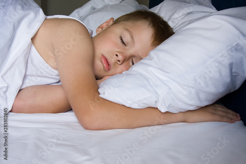 Tired young boy sleeping in bedroom