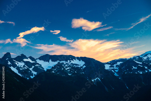 Alpenglow on clouds over a rugged mountain range in Mt. Rainier National Park.