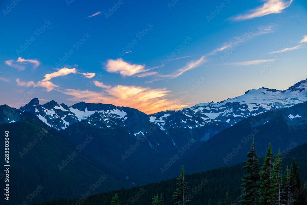Alpenglow on clouds over a rugged mountain range in Mt. Rainier National Park.