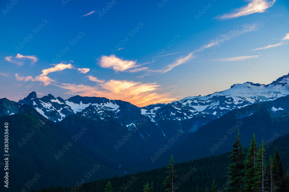 Fototapeta premium Alpenglow on clouds over a rugged mountain range in Mt. Rainier National Park.