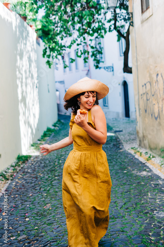 Happy girl dancing and eating a pastel de nata in Lisbon photo