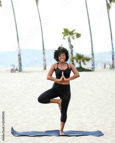 Portrait of smiling woman doing yoga on beach