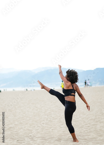 Woman doing high kick on beach