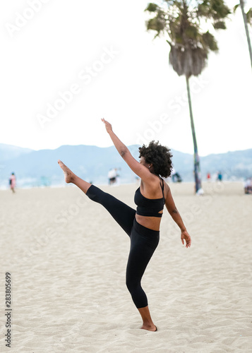 Woman doing high kick on beach