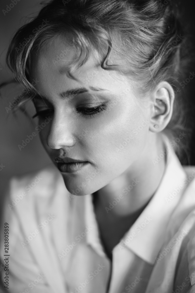 Young blonde woman in a casual white shirt and jeans in a loft interior, close up fashion portrait Young blonde woman in a casual white shirt and jeans in a loft interior, close up fashion portrait