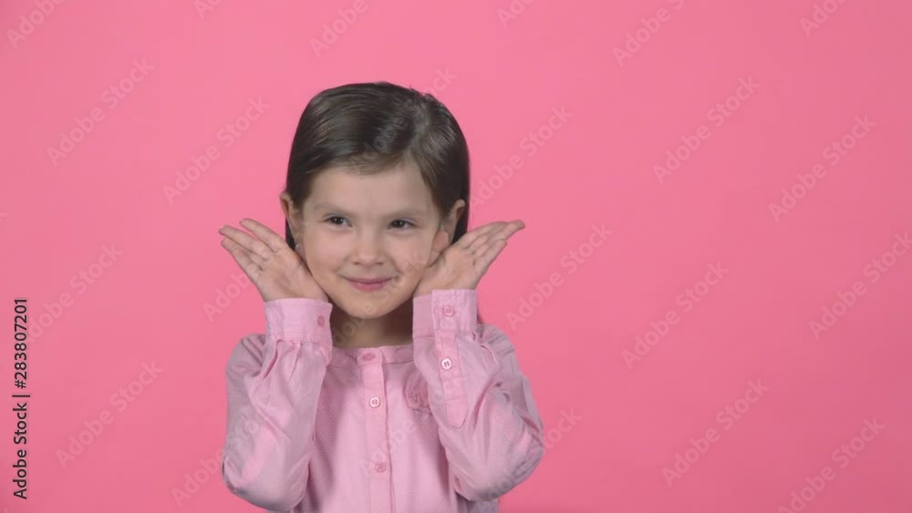 Little female is hiding face with hands on pink background. Slow motion Little female is hiding face with hands on pink background. Slow motion