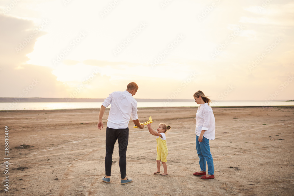 Happy family playing with toy airplane on the beach on sunset. Dreams of being a child Happy family playing with toy airplane on the beach on sunset. Dreams of being a child