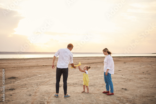 Happy family playing with toy airplane on the beach on sunset. Dreams of being a child © oes