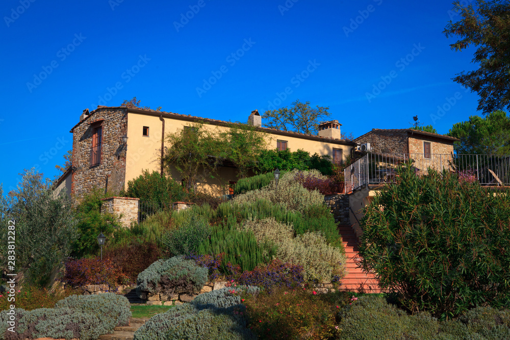Typical Italian rural house with restaurant in lush vegetation in the afternoon in summer.