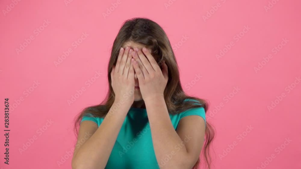Little female is scared and hiding her face in studio on pink background. Slow motion Little female is scared and hiding her face in studio on pink background. Slow motion