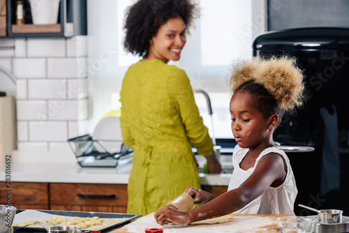 Mother Teaching Child to Cook and Help in the Kitchen. African American Mother and Daughter making cookies at home. 